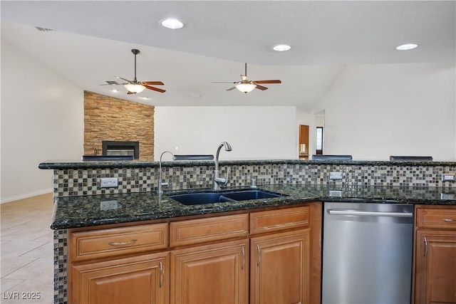 kitchen with sink, dishwasher, lofted ceiling, light tile patterned floors, and dark stone counters