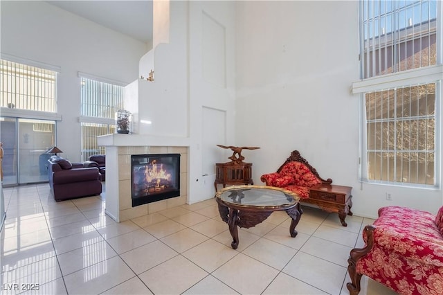 sitting room featuring a towering ceiling, light tile patterned flooring, and a tile fireplace