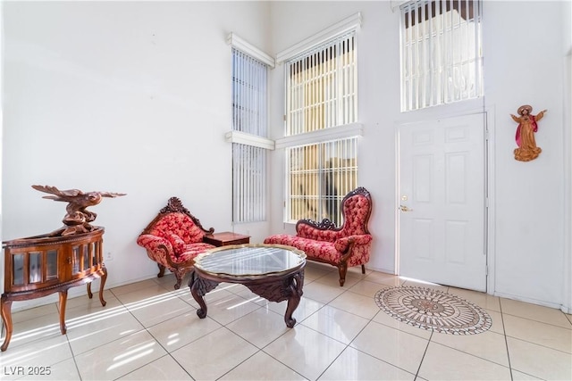 sitting room featuring a towering ceiling and light tile patterned flooring