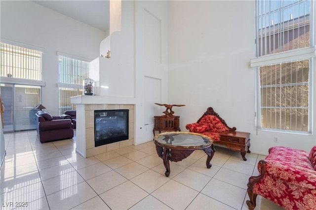 living area featuring a high ceiling, a tile fireplace, and light tile patterned floors