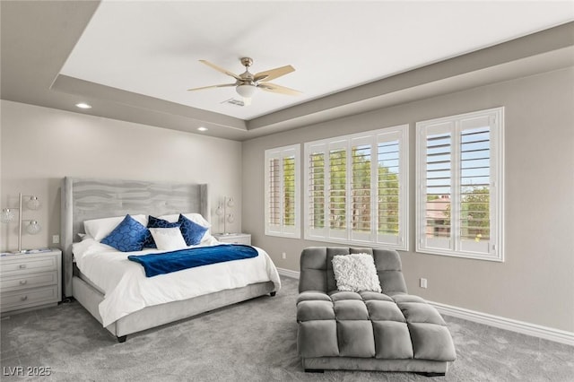 carpeted bedroom featuring a raised ceiling and ceiling fan