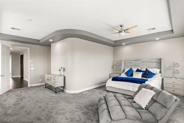 carpeted bedroom featuring ceiling fan and a tray ceiling