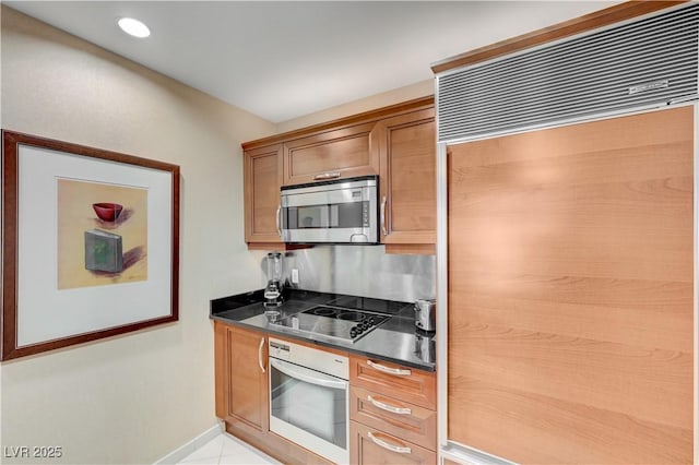 kitchen with black electric cooktop, paneled refrigerator, light tile patterned floors, and oven