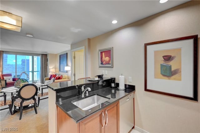 kitchen with kitchen peninsula, sink, white dishwasher, dark stone countertops, and light brown cabinets