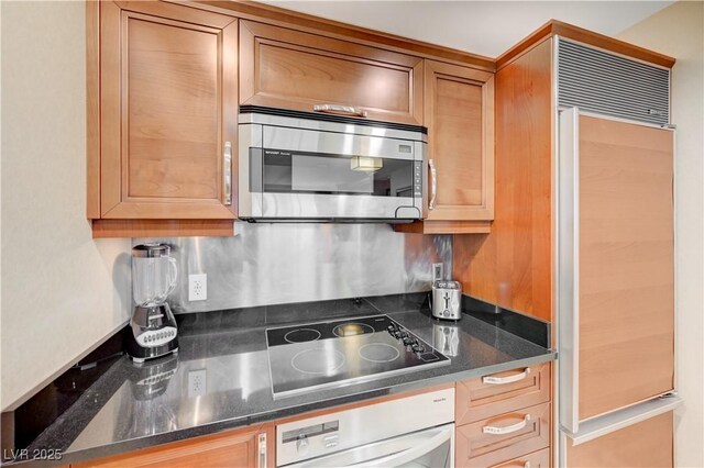 kitchen with stainless steel appliances, dark stone counters, and tasteful backsplash