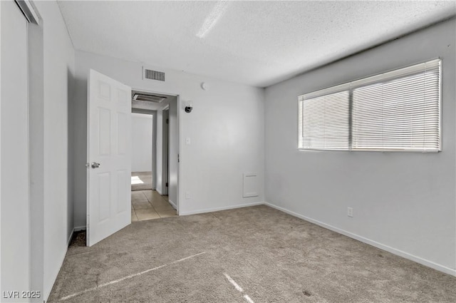 unfurnished bedroom with a textured ceiling and light colored carpet