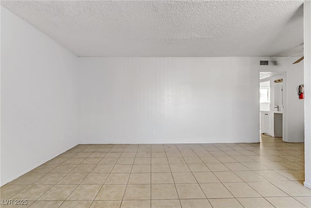 tiled spare room with sink and a textured ceiling