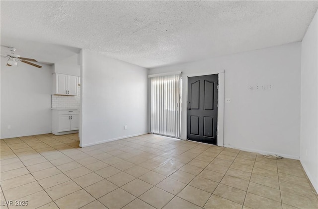 spare room featuring a textured ceiling, ceiling fan, and light tile patterned flooring