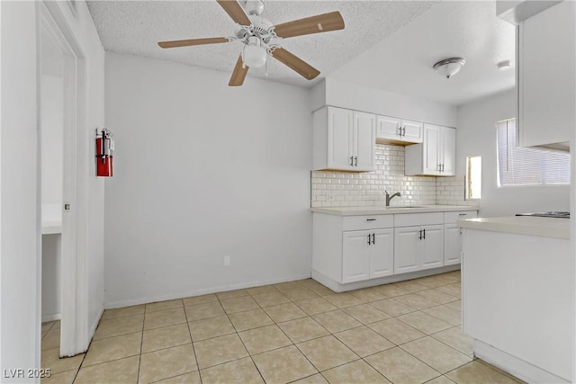 kitchen featuring sink, a textured ceiling, white cabinetry, ceiling fan, and light tile patterned floors