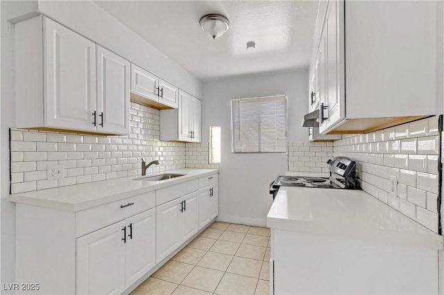 kitchen featuring stainless steel range with electric cooktop, sink, white cabinetry, light tile patterned floors, and tasteful backsplash