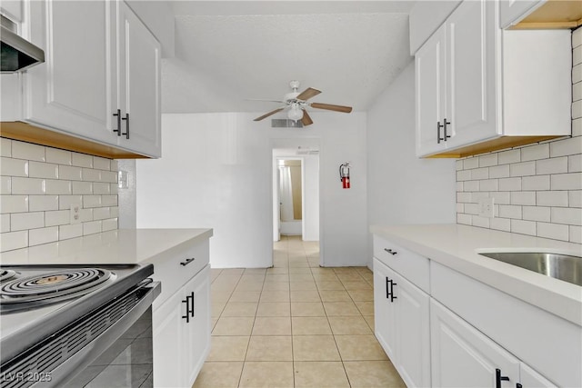 kitchen with white cabinets, wall chimney range hood, backsplash, and light tile patterned flooring