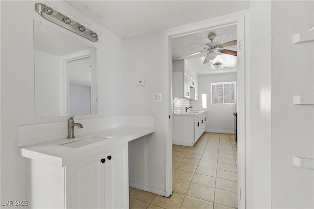 bathroom with tile patterned flooring, vanity, ceiling fan, a textured ceiling, and tasteful backsplash