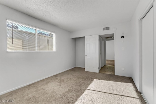 unfurnished bedroom featuring a textured ceiling, a closet, and light carpet