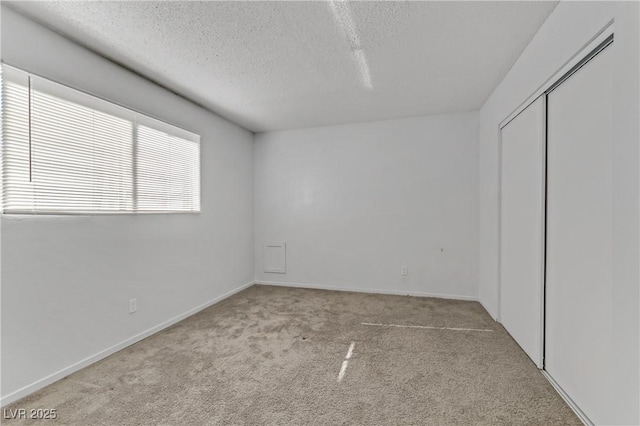 unfurnished bedroom featuring a textured ceiling and light carpet