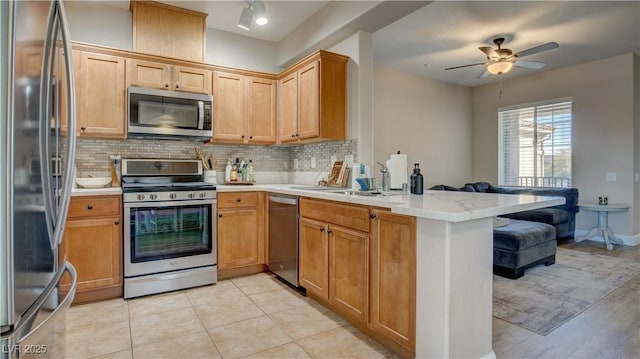 kitchen with kitchen peninsula, decorative backsplash, appliances with stainless steel finishes, ceiling fan, and sink