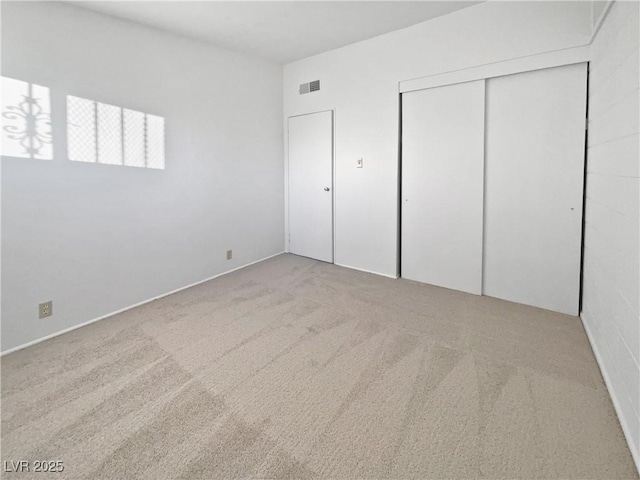 unfurnished bedroom with light colored carpet and a closet