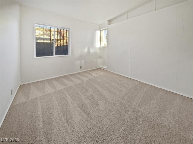 carpeted spare room with a wealth of natural light and lofted ceiling