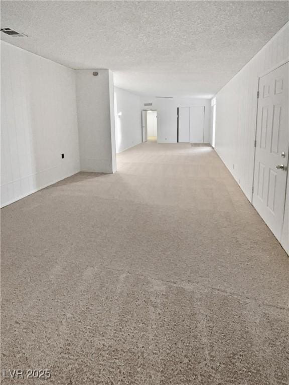 empty room with a textured ceiling and light carpet