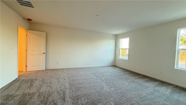 spare room with carpet floors, visible vents, and baseboards