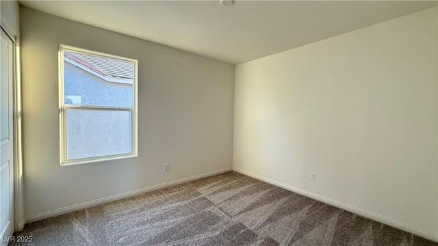 spare room featuring carpet and baseboards