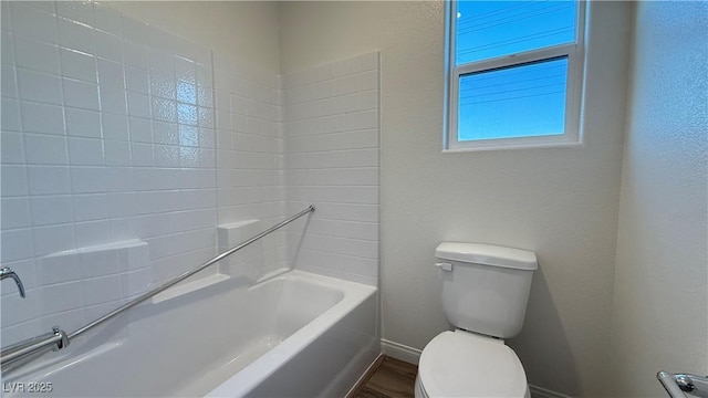 full bathroom featuring toilet, baseboards, wood finished floors, and a textured wall