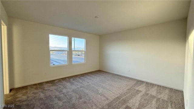 carpeted spare room featuring baseboards