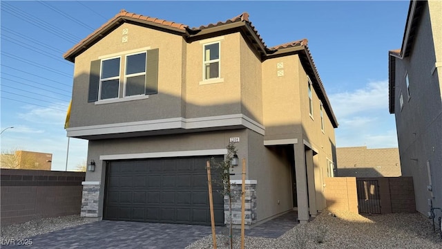 view of front of property with decorative driveway, a tile roof, stucco siding, fence, and a garage