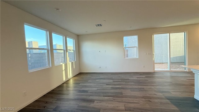 spare room featuring dark wood-type flooring, visible vents, and baseboards