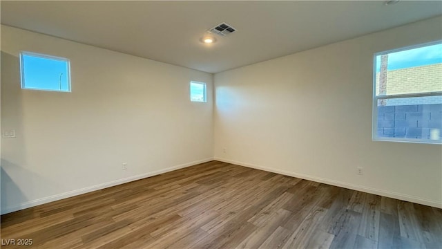 spare room featuring baseboards, visible vents, and wood finished floors