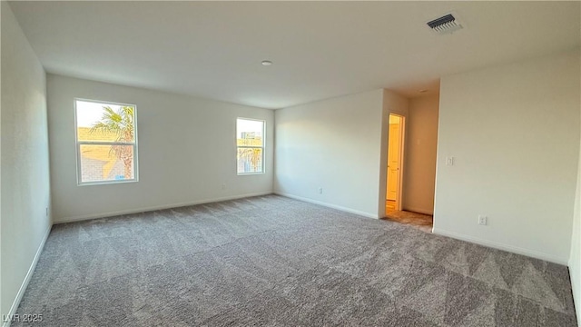 spare room featuring carpet floors, baseboards, and visible vents