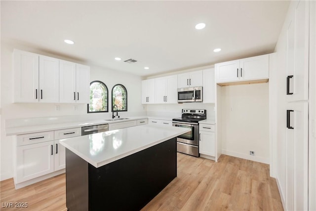 kitchen with stainless steel appliances, a kitchen island, and white cabinets