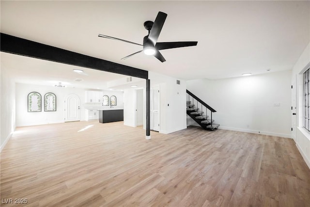 unfurnished living room featuring ceiling fan, light wood-type flooring, and beamed ceiling