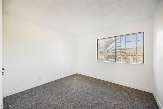 spare room featuring a textured ceiling and dark colored carpet