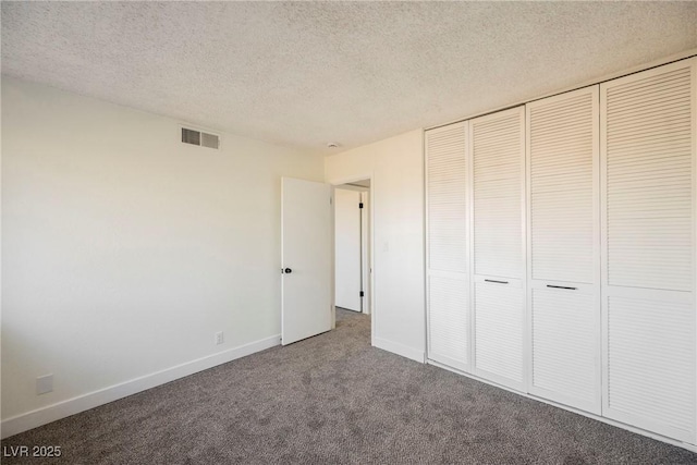 unfurnished bedroom featuring a textured ceiling, a closet, and carpet floors