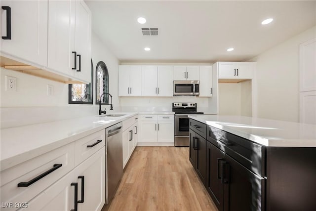 kitchen featuring appliances with stainless steel finishes, light hardwood / wood-style flooring, and white cabinets