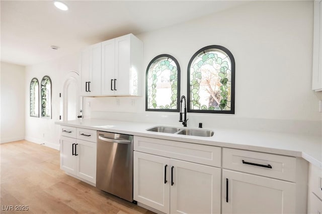 kitchen featuring stainless steel dishwasher, white cabinets, sink, and light hardwood / wood-style flooring