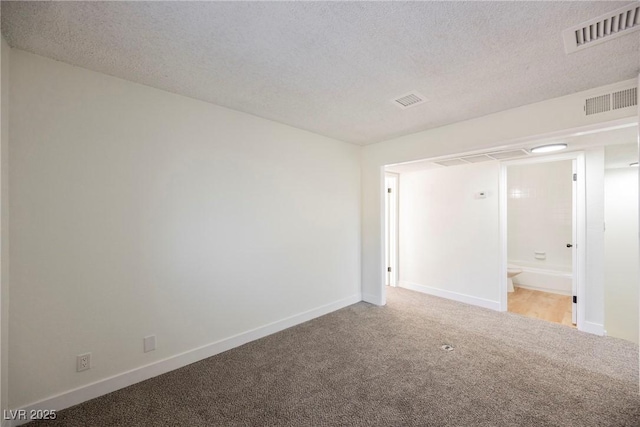 empty room with a textured ceiling and light carpet