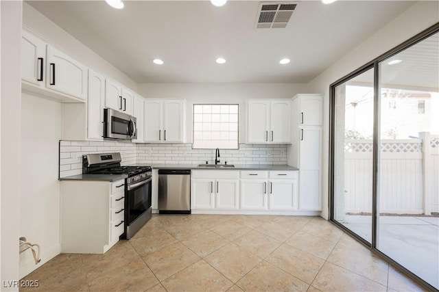 kitchen featuring appliances with stainless steel finishes, white cabinetry, decorative backsplash, and sink