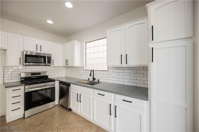 kitchen with stainless steel appliances, white cabinets, decorative backsplash, and sink