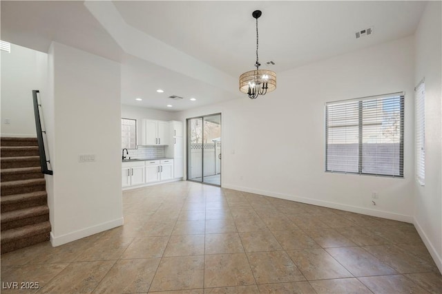 unfurnished living room with sink, an inviting chandelier, and light tile patterned floors