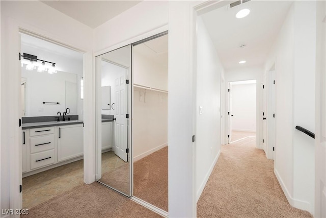 corridor featuring light carpet and sink