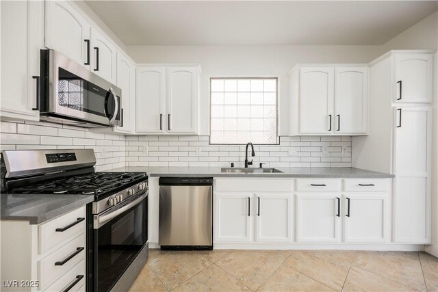 kitchen with white cabinets, appliances with stainless steel finishes, backsplash, and sink