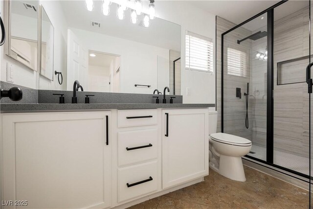 bathroom with toilet, vanity, and a shower with shower door