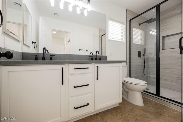 bathroom with vanity, toilet, and a shower with door