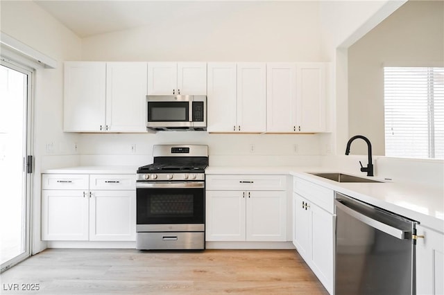 kitchen featuring appliances with stainless steel finishes, white cabinets, and sink