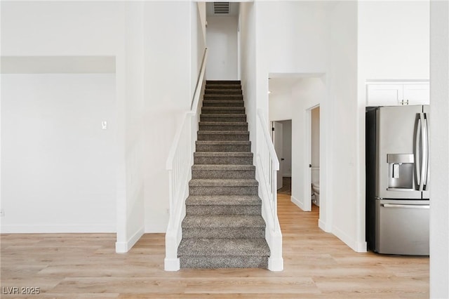 stairway featuring a high ceiling and hardwood / wood-style floors