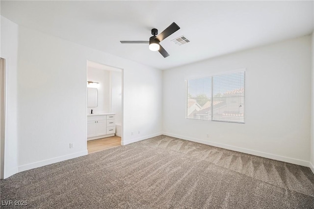 unfurnished bedroom featuring ceiling fan, light colored carpet, and ensuite bath