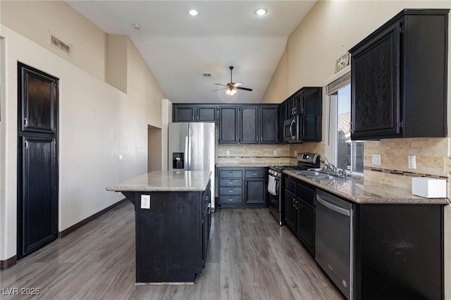 kitchen with light stone counters, stainless steel appliances, a center island, and backsplash