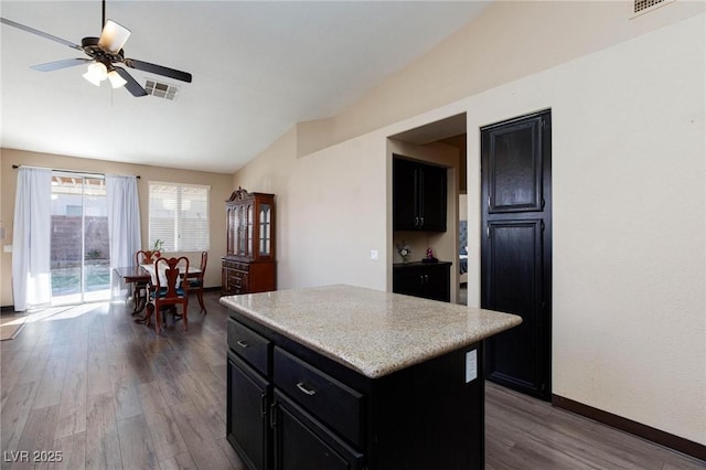 kitchen featuring ceiling fan, dark wood-type flooring, vaulted ceiling, and a kitchen island