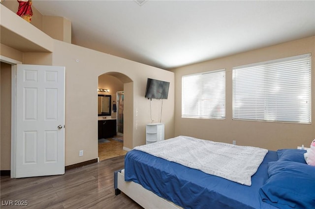 bedroom featuring ensuite bath and dark wood-type flooring